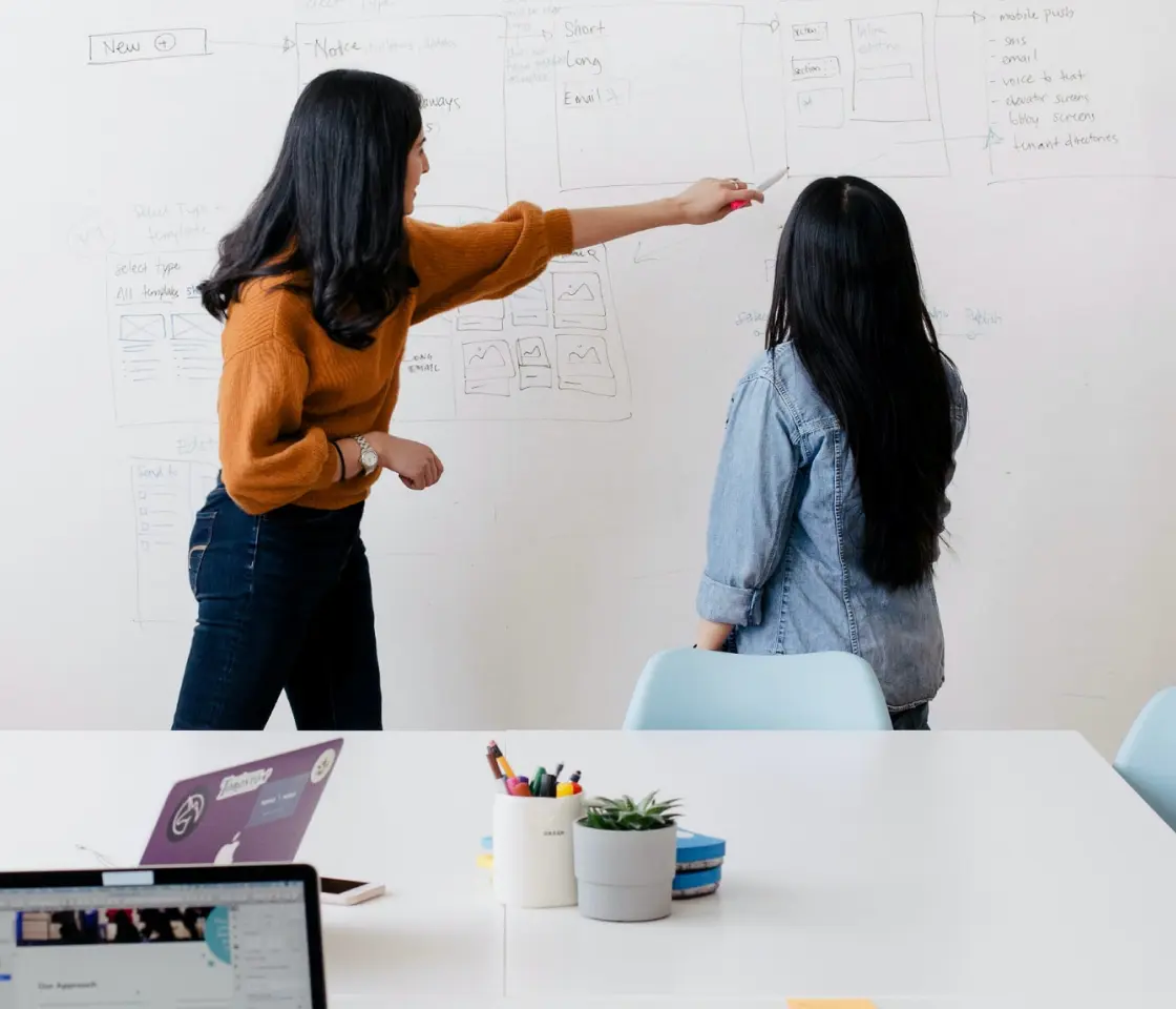 Two women using a whiteboard